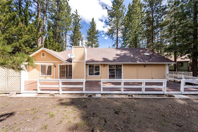 rear view of property featuring roof with shingles, fence, and a wooden deck