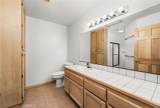bathroom featuring toilet, tile patterned flooring, vanity, and baseboards