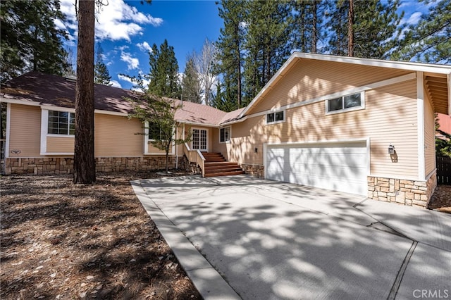 view of front of home featuring stone siding, a garage, and driveway