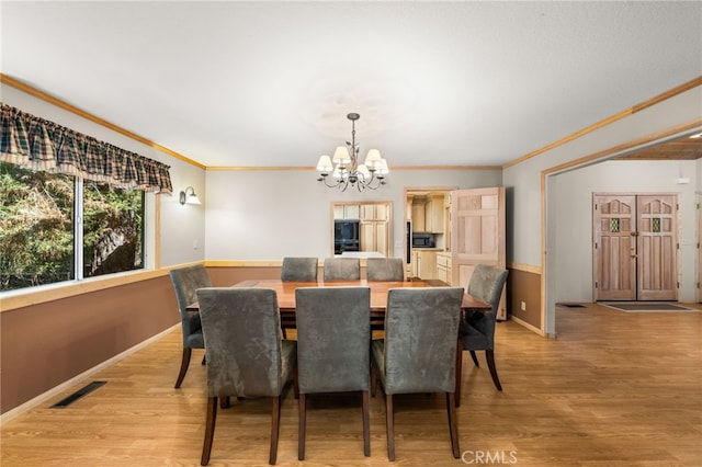 dining space featuring a chandelier, crown molding, light wood-type flooring, and baseboards