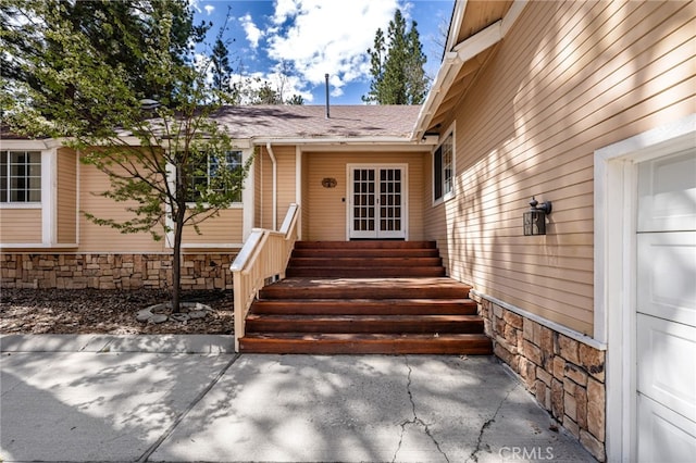 view of exterior entry with roof with shingles