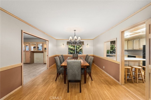 dining room with ornamental molding, light wood finished floors, a chandelier, and baseboards