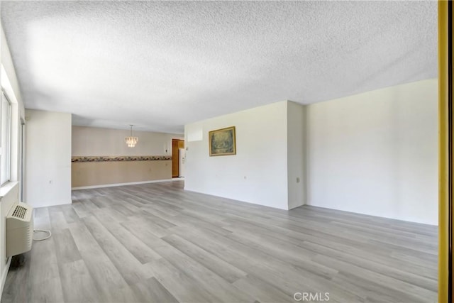 2384 Via Mariposa W Unit 3G, Laguna Woods, CA 92637 - spare room with a textured ceiling, a chandelier, and light wood-style flooring