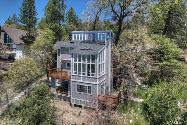27757 N Bay Rd, Lake Arrowhead, CA 92352 - back of house with a wooden deck, roof with shingles, view of wooded area, and a sunroom