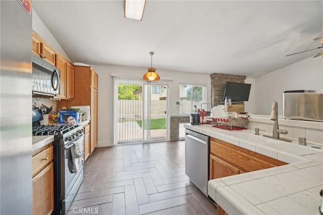 2925 Greenbriar Dr, Ontario, CA 91761 - kitchen featuring stainless steel appliances, open floor plan, tile counters, a sink, and brown cabinetry