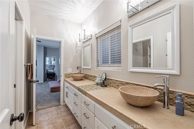full bath featuring double vanity, a textured wall, and tile patterned flooring