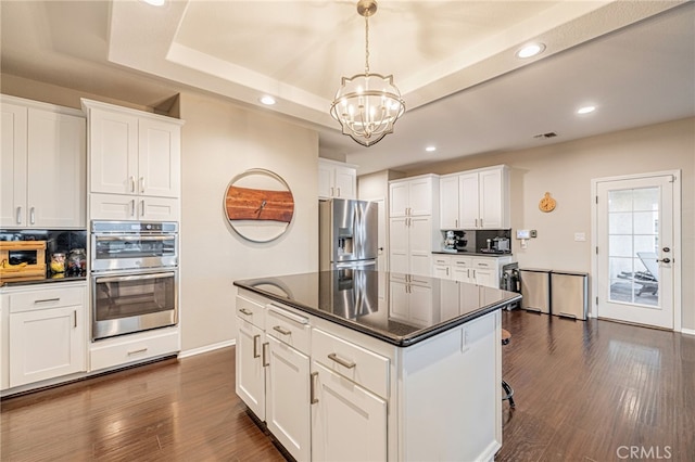 kitchen featuring appliances with stainless steel finishes, a tray ceiling, dark countertops, a chandelier, and recessed lighting