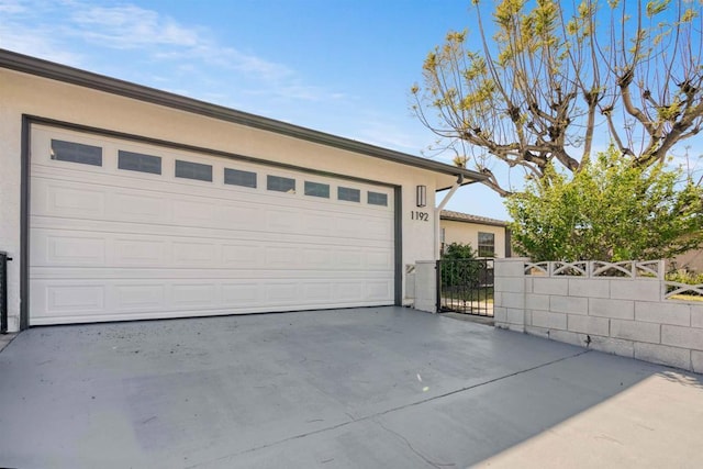 garage featuring fence and concrete driveway