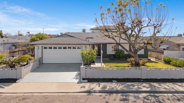 view of front of property featuring an attached garage, a fenced front yard, and driveway