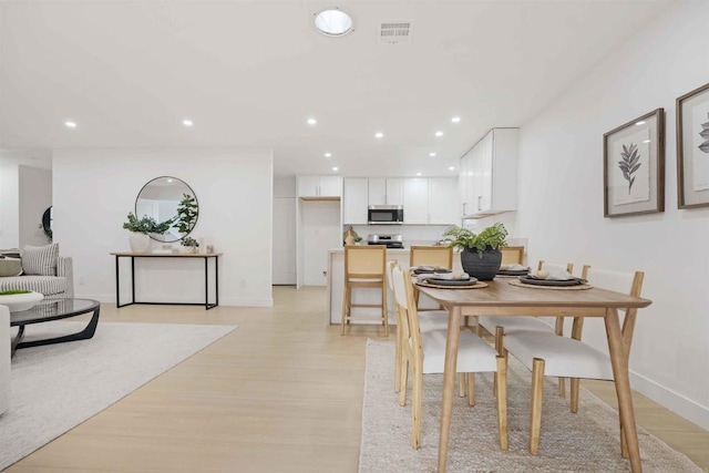 dining area with recessed lighting, light wood-style flooring, and baseboards