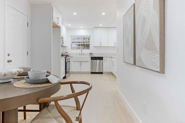 kitchen with stainless steel appliances, a sink, white cabinets, light countertops, and recessed lighting