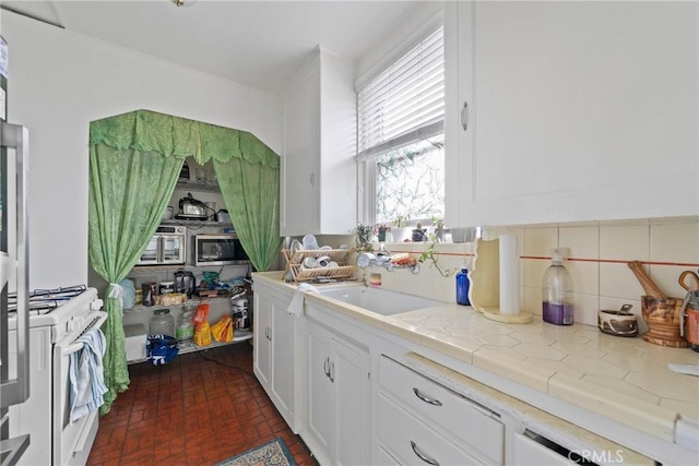 1801 N Ross St, Santa Ana, CA 92706 - kitchen featuring white gas range oven, brick patterned flooring, white cabinets, decorative backsplash, and a sink