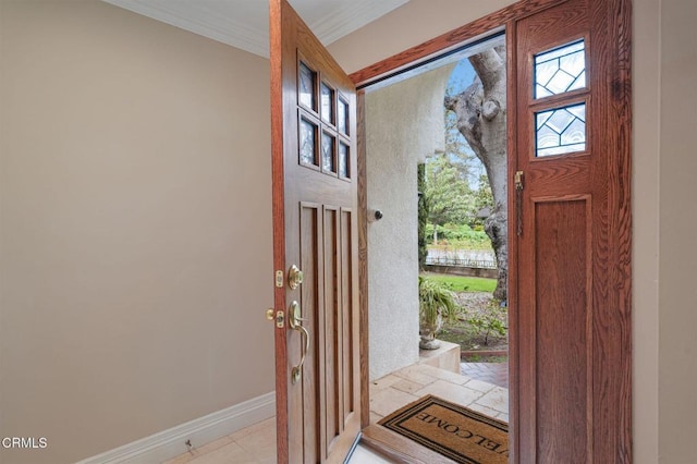 entryway with baseboards and crown molding