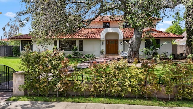 mediterranean / spanish-style home with a tiled roof, a gate, and stucco siding
