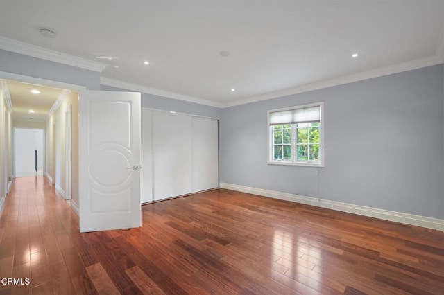 unfurnished bedroom with wood-type flooring, a closet, baseboards, crown molding, and recessed lighting