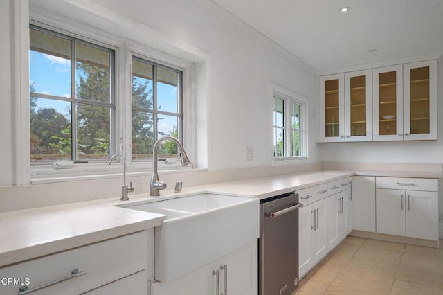 kitchen featuring stainless steel dishwasher, a sink, white cabinets, glass insert cabinets, and light tile patterned floors