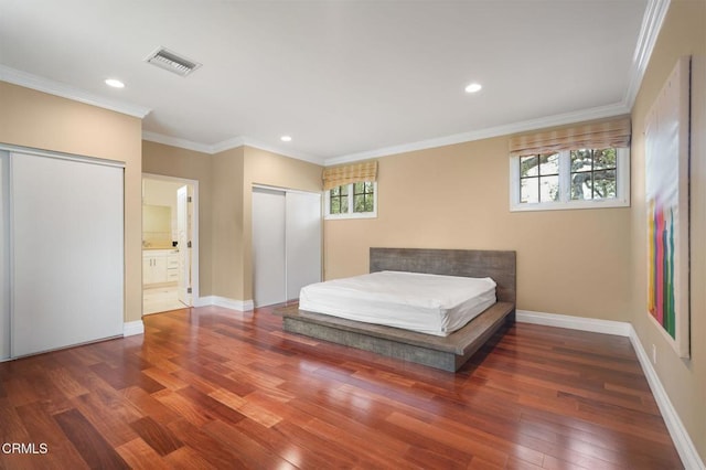 bedroom with wood finished floors, recessed lighting, baseboards, ornamental molding, and ensuite bathroom