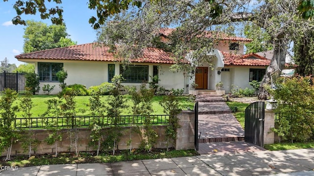 view of front of property featuring a tile roof, stucco siding, and a gate