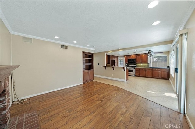 10059 Rock Hl, Moreno Valley, CA 92557 - unfurnished living room with light wood-type flooring, baseboards, a textured ceiling, a brick fireplace, and crown molding