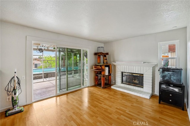 4176 Canyonside Cir, Jurupa Valley, CA 92509 - unfurnished living room with light wood-style floors, healthy amount of natural light, a textured ceiling, and a fireplace