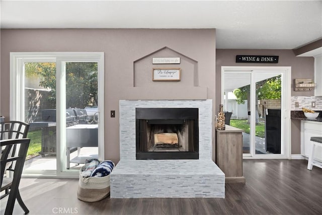 living room featuring a fireplace with raised hearth and wood finished floors