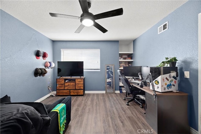 office featuring wood finished floors, ceiling fan, a textured wall, a textured ceiling, and baseboards