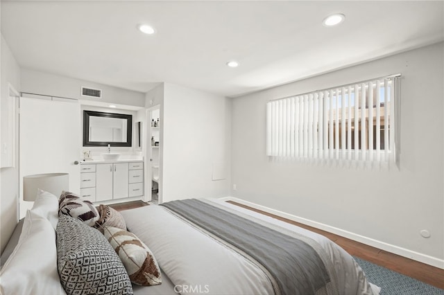 bedroom featuring wood finished floors, a sink, baseboards, recessed lighting, and ensuite bathroom
