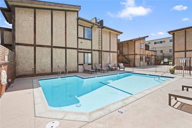 community pool with fence and a patio