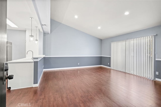 unfurnished living room with vaulted ceiling, dark wood-type flooring, baseboards, recessed lighting, and a sink