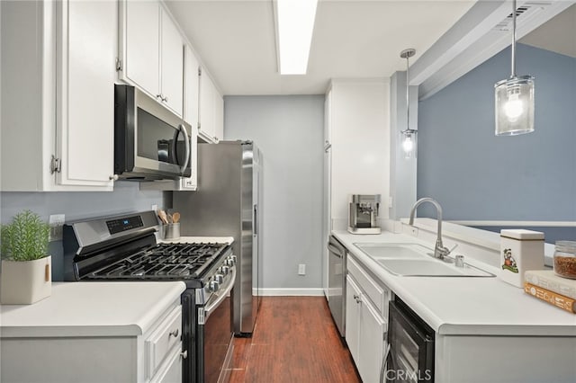 kitchen featuring stainless steel appliances, a sink, dark wood-style floors, baseboards, and light countertops
