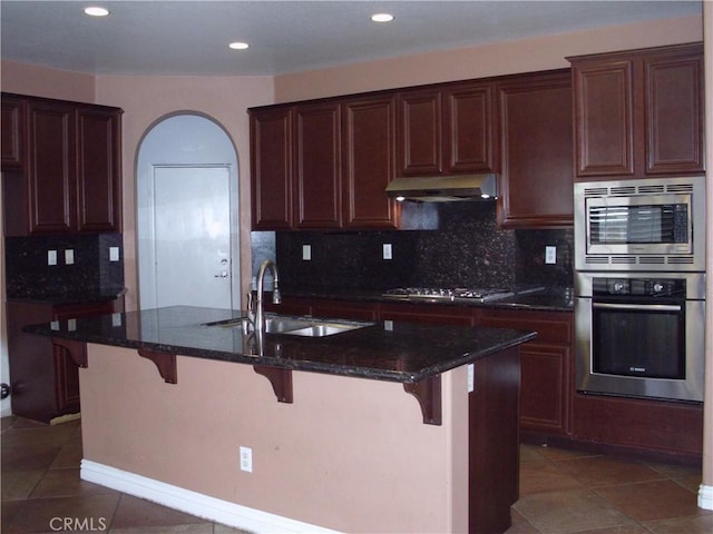 1110 Laurelhurst, San Jacinto, CA 92582 - kitchen featuring appliances with stainless steel finishes, under cabinet range hood, a sink, backsplash, and dark stone countertops