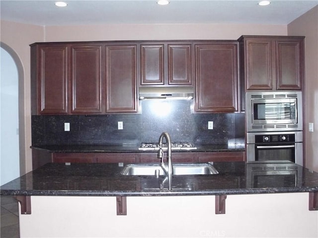 1110 Laurelhurst, San Jacinto, CA 92582 - kitchen with appliances with stainless steel finishes, a breakfast bar, under cabinet range hood, arched walkways, and recessed lighting