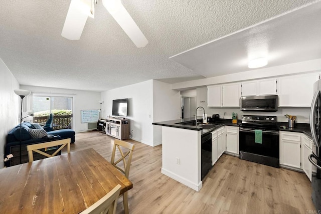 kitchen with black appliances, a peninsula, a textured ceiling, open floor plan, and dark countertops