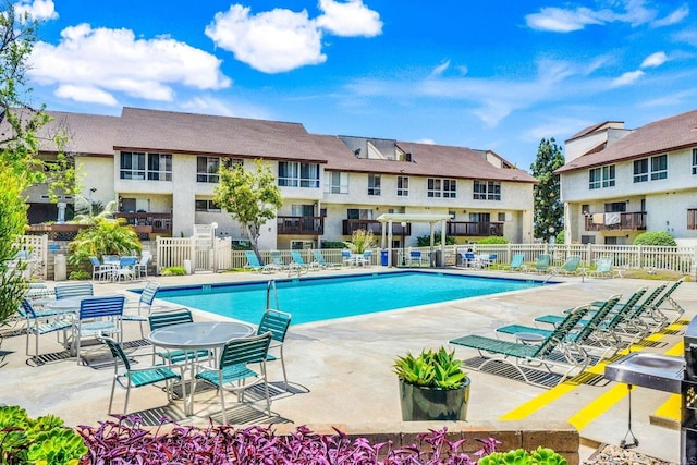 community pool with fence, a patio area, and a residential view