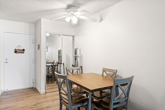 dining space with ceiling fan, light wood-style floors, and a textured ceiling