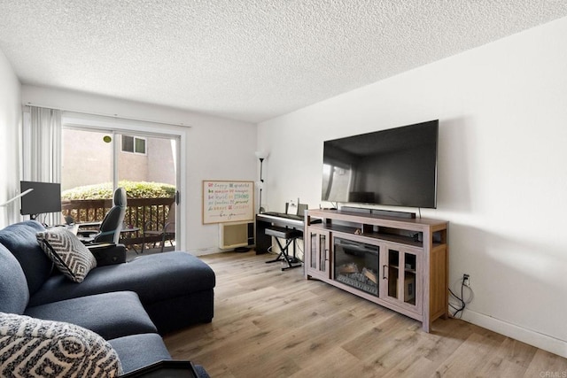 living room featuring wood finished floors, a textured ceiling, and baseboards
