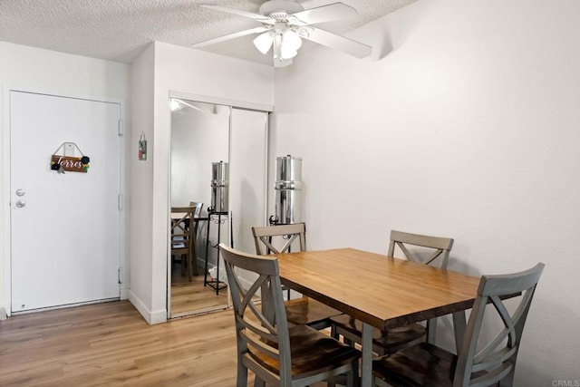 dining space with light wood-style flooring, ceiling fan, a textured ceiling, and baseboards