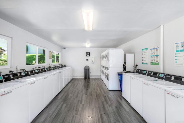 community laundry with separate washer and dryer, dark wood-style flooring, estacked washer and dryer, and baseboards