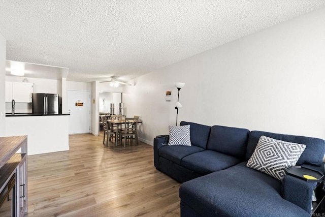 living room with light wood-style flooring, a textured ceiling, and ceiling fan