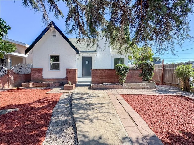 view of front of property featuring fence, stucco siding, and brick siding