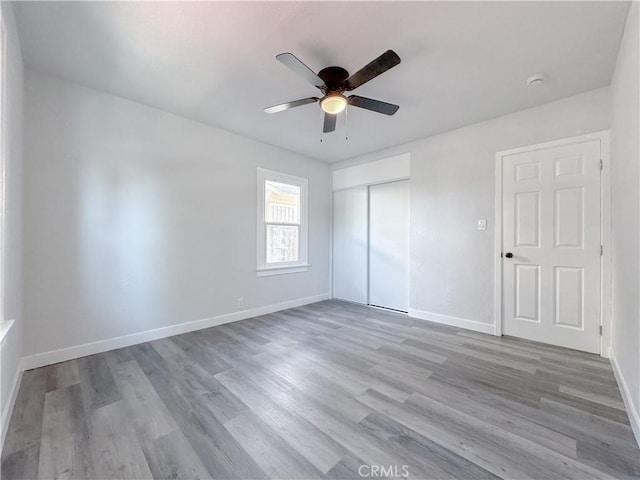 unfurnished bedroom featuring a closet, wood finished floors, baseboards, and a ceiling fan
