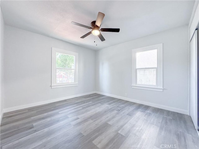spare room featuring wood finished floors, a ceiling fan, and baseboards