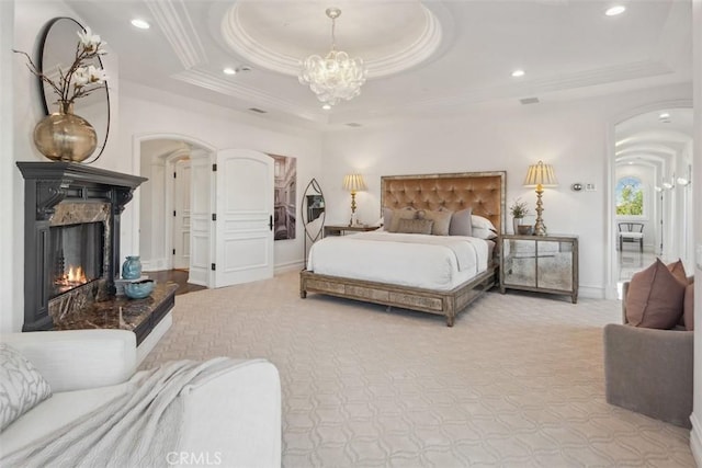 28 Shoreridge, Newport Coast, CA 92657 - carpeted bedroom with arched walkways, crown molding, a warm lit fireplace, a chandelier, and a raised ceiling