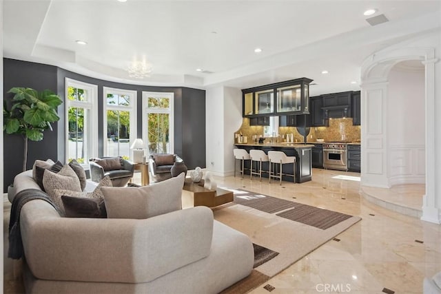 28 Shoreridge, Newport Coast, CA 92657 - living area featuring light marble finish flooring, a raised ceiling, recessed lighting, a chandelier, and decorative columns