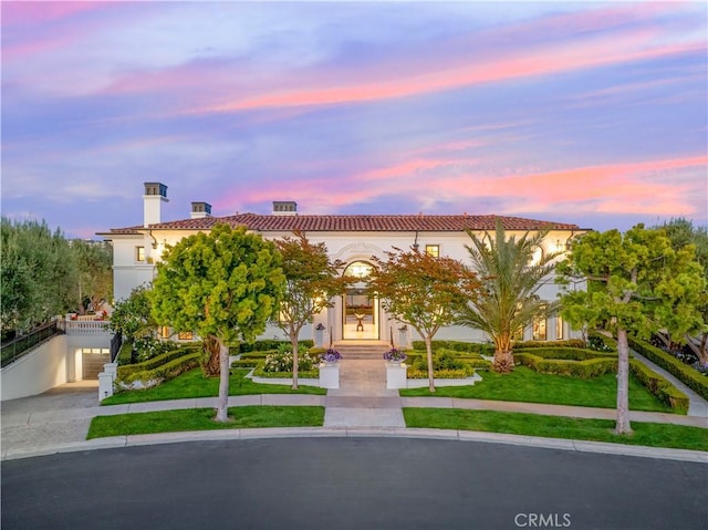 28 Shoreridge, Newport Coast, CA 92657 - view of front facade featuring stucco siding, a tile roof, a chimney, concrete driveway, and a lawn