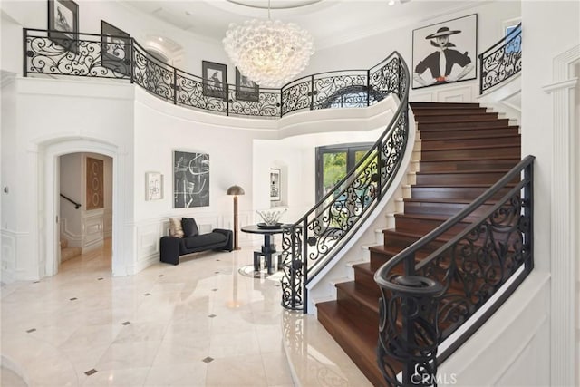 28 Shoreridge, Newport Coast, CA 92657 - entrance foyer featuring arched walkways, stairs, a chandelier, ornamental molding, and a decorative wall