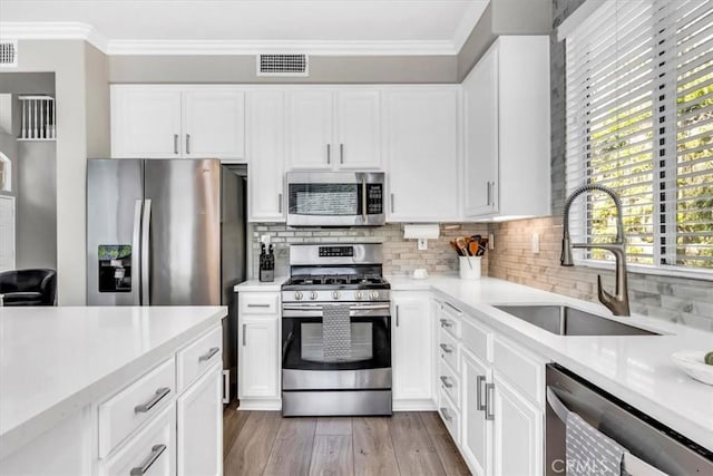 73 Melrose Dr, Mission Viejo, CA 92692 - kitchen featuring stainless steel appliances, a sink, crown molding, light countertops, and backsplash