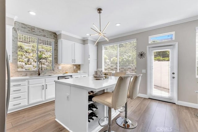 73 Melrose Dr, Mission Viejo, CA 92692 - kitchen featuring a sink, light countertops, backsplash, light wood-style floors, and crown molding