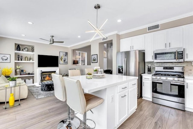 73 Melrose Dr, Mission Viejo, CA 92692 - kitchen with appliances with stainless steel finishes, light countertops, a center island, light wood finished floors, and crown molding