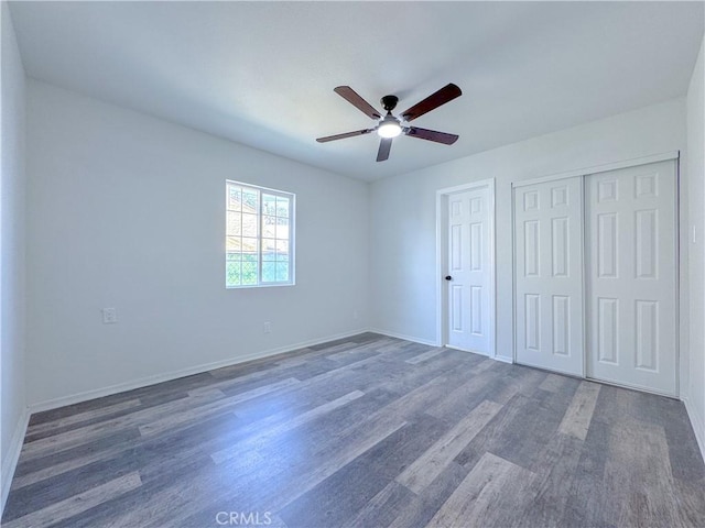 unfurnished bedroom with wood finished floors, a closet, a ceiling fan, and baseboards